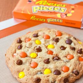 one giant peanut butter Reese's Pieces cookie on a silpat baking mat