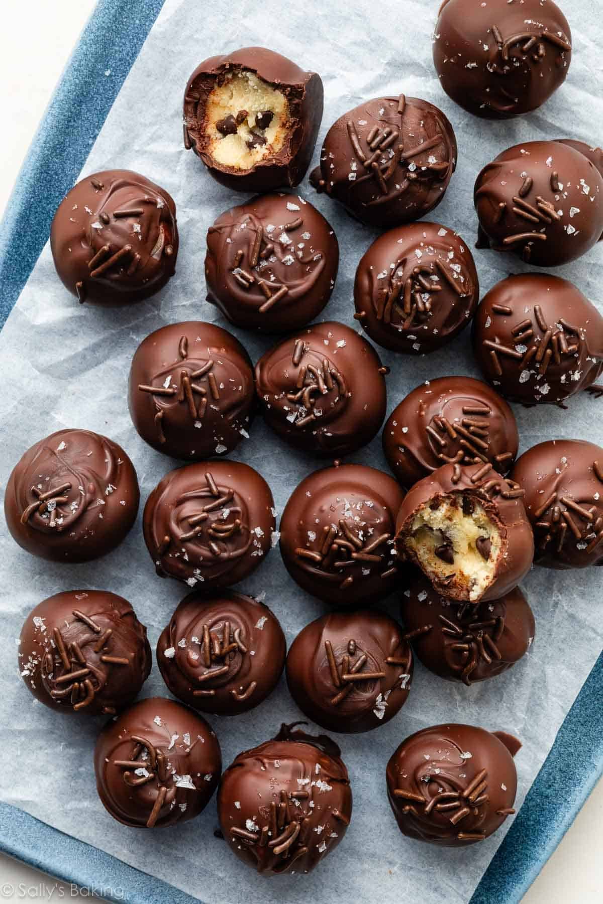 cookie dough truffles covered in chocolate and topped with chocolate sprinkles and sea salt.