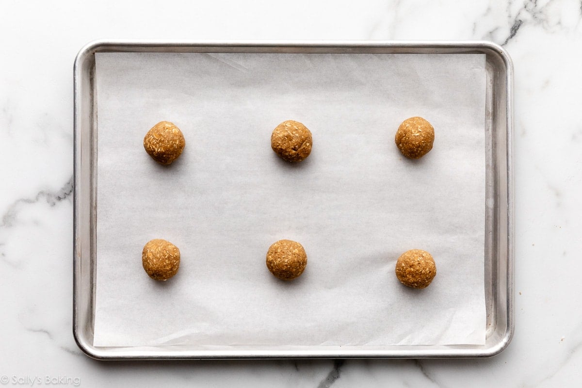 6 balls of cookie dough on parchment paper-lined baking sheet.