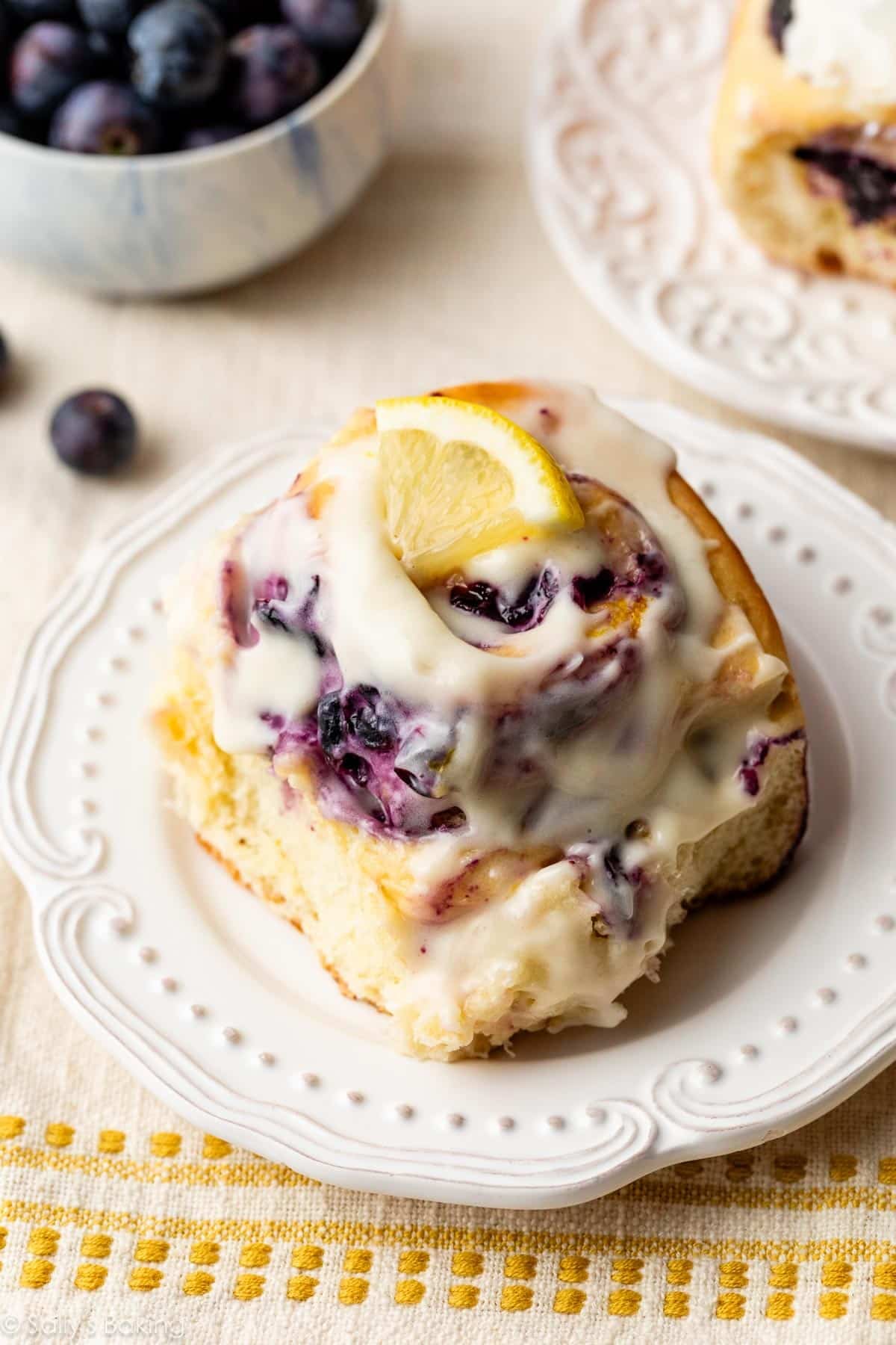 blueberry lemon roll with cream cheese icing on a white plate.