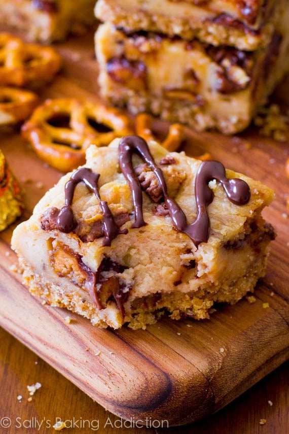 peanut butter cup pretzel cheesecake bar on a wood board