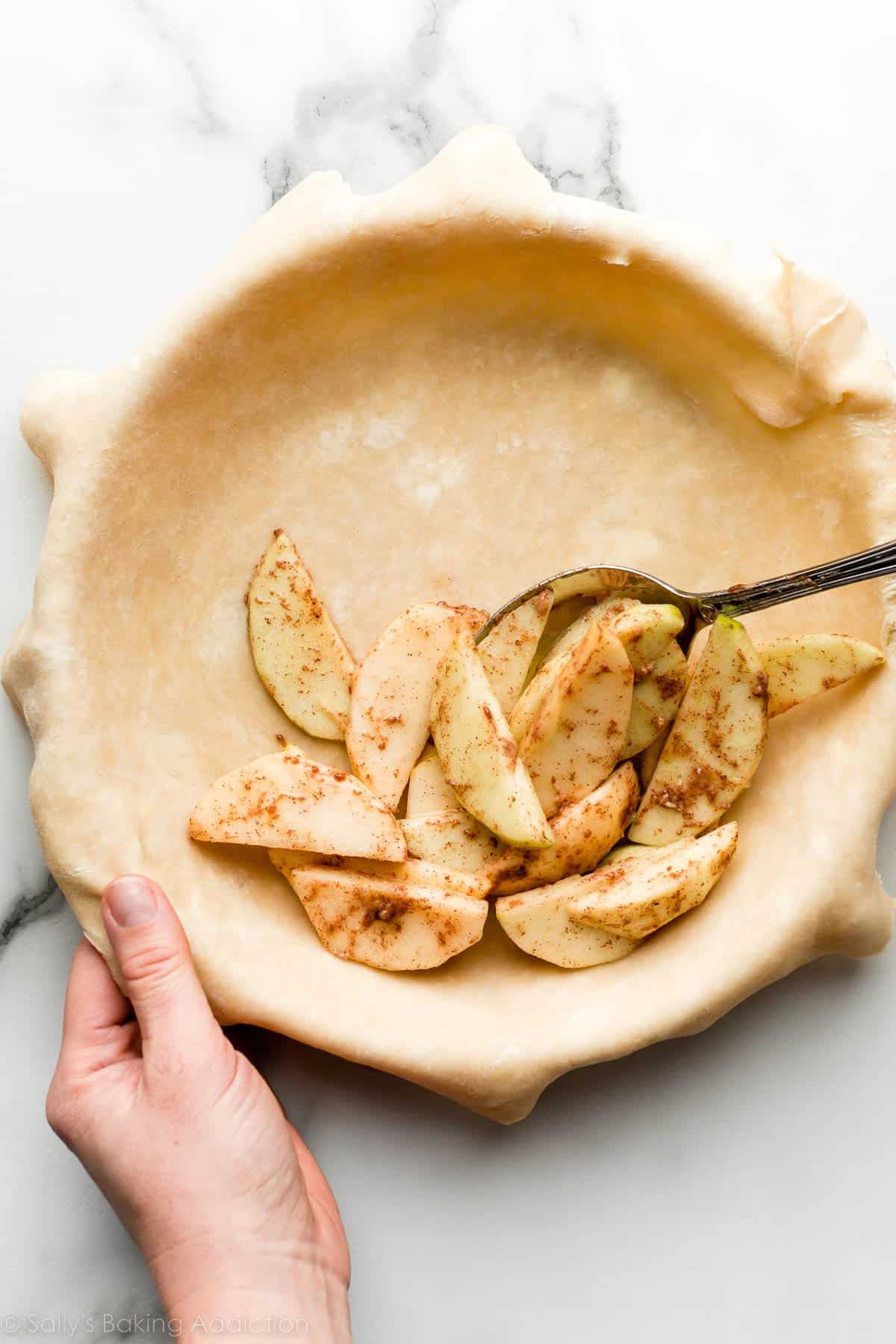 spooning apples into pie dough.