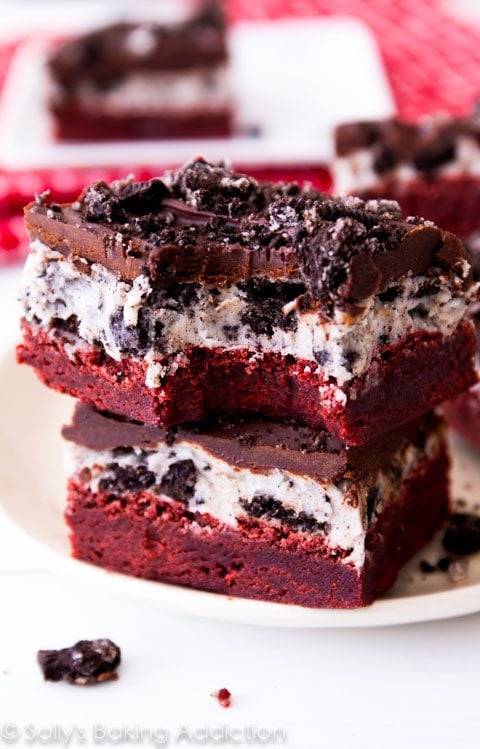 stack of red velvet Oreo brownies on a white plate with a bite taken from one