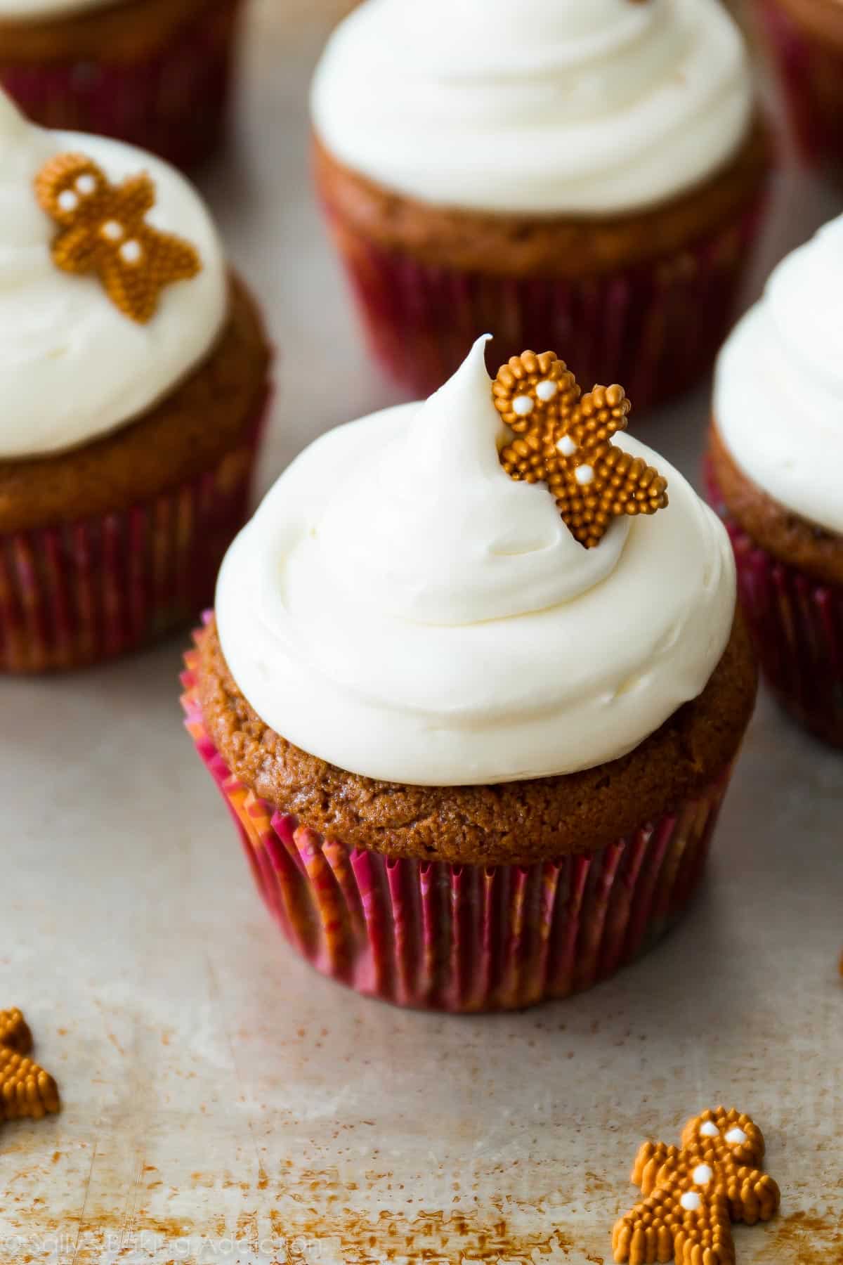 gingerbread cupcakes topped with cream cheese frosting and a decorative gingerbread man candy