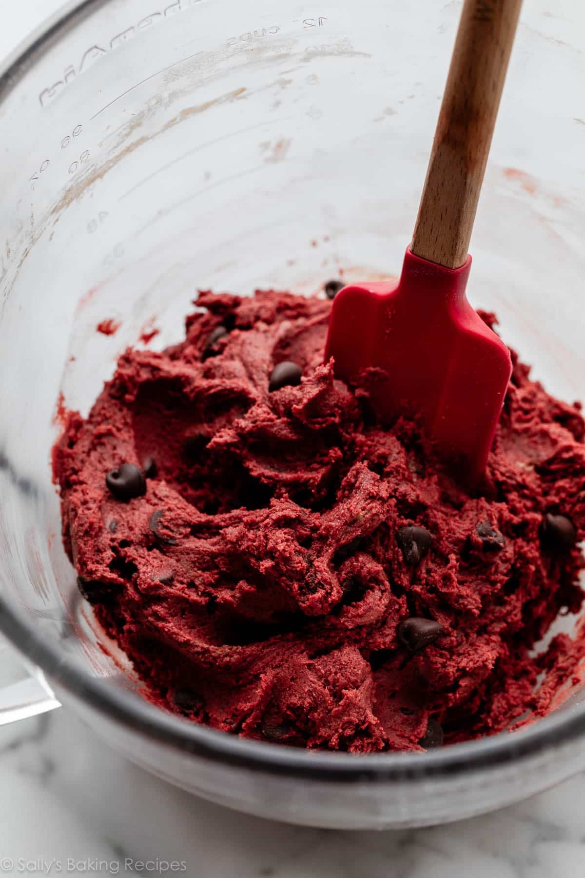 red dough with chocolate chips in glass bowl.