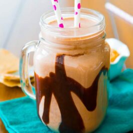chocolate peanut butter smoothie in a glass mug with straws
