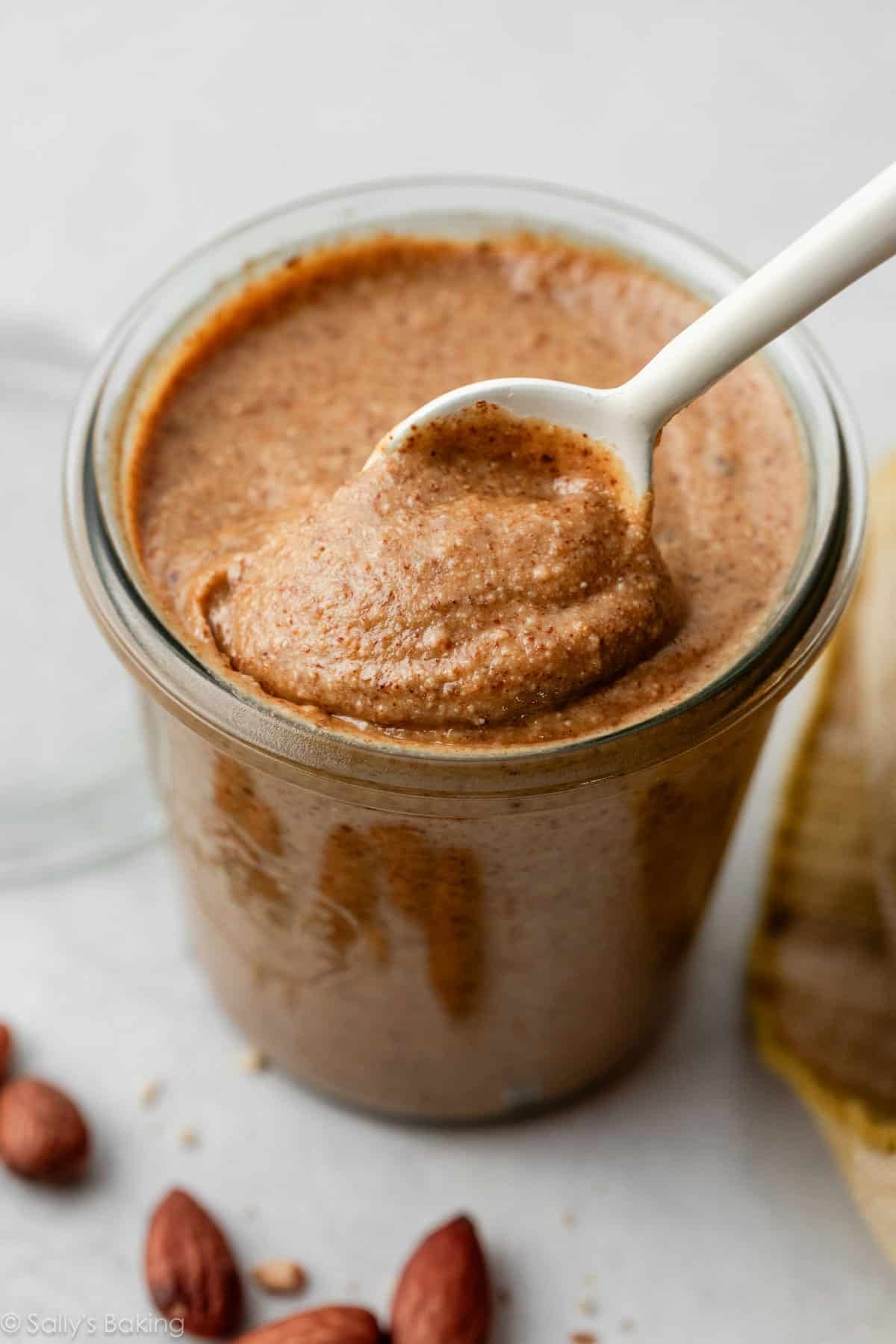 homemade almond butter in jar with white spoon.