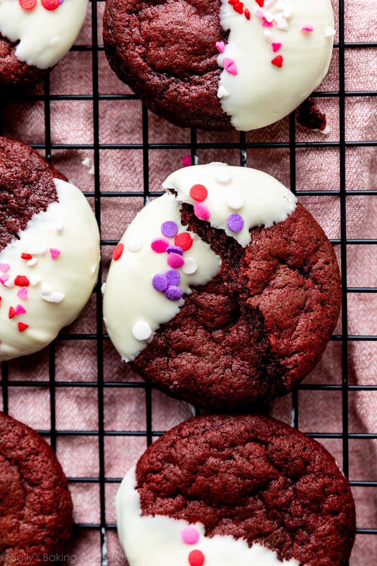 red velvet cookies dipped in white chocolate with Valentine's Day heart sprinkles on top