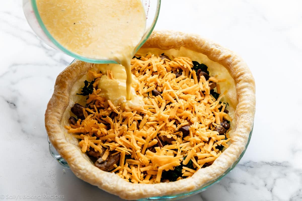 pouring egg mixture over cheese and mushrooms in pie crust.