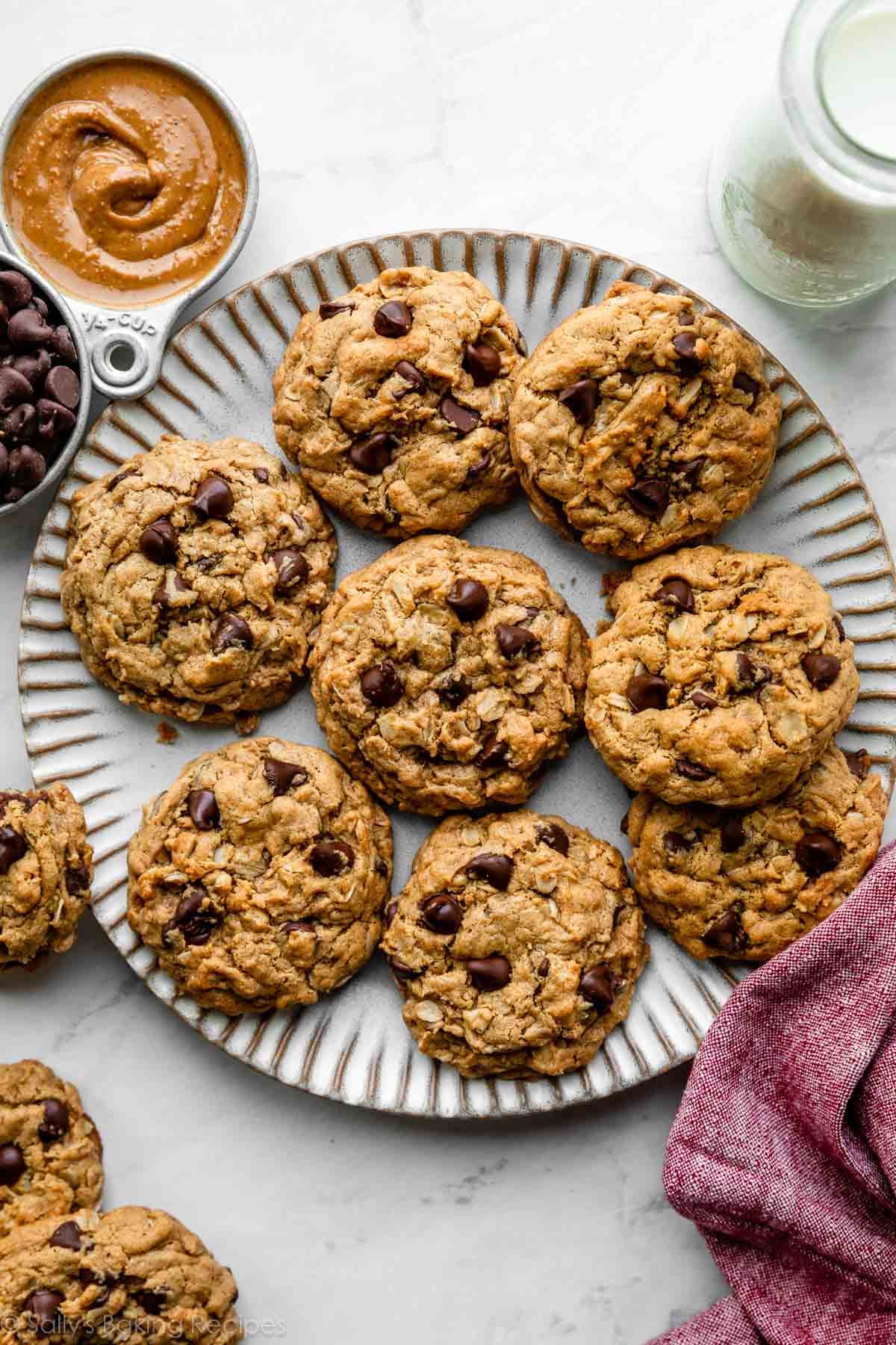 peanut butter oatmeal cookies arranged on gray plate with milk and measuring cups next to it.