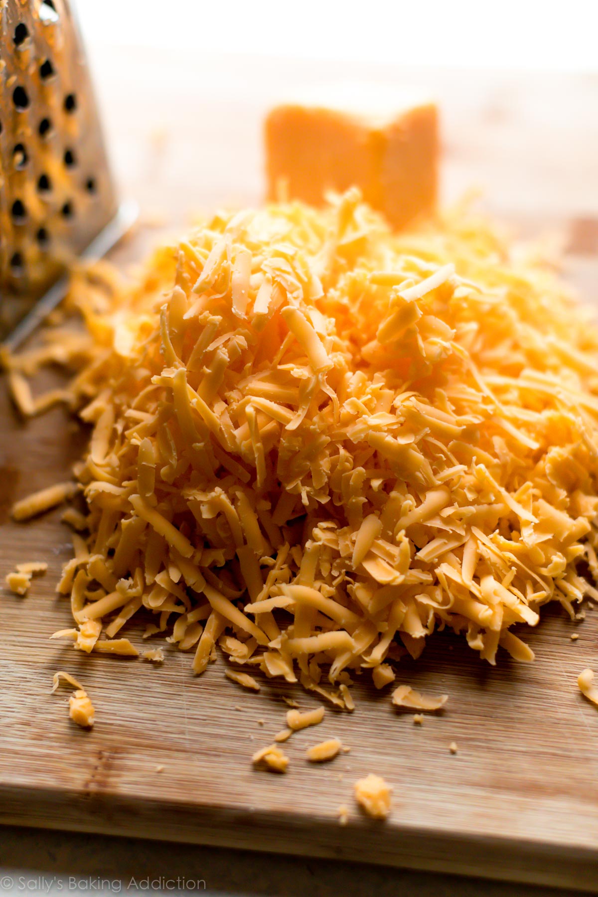 Shredded cheddar cheese on a wood cutting board