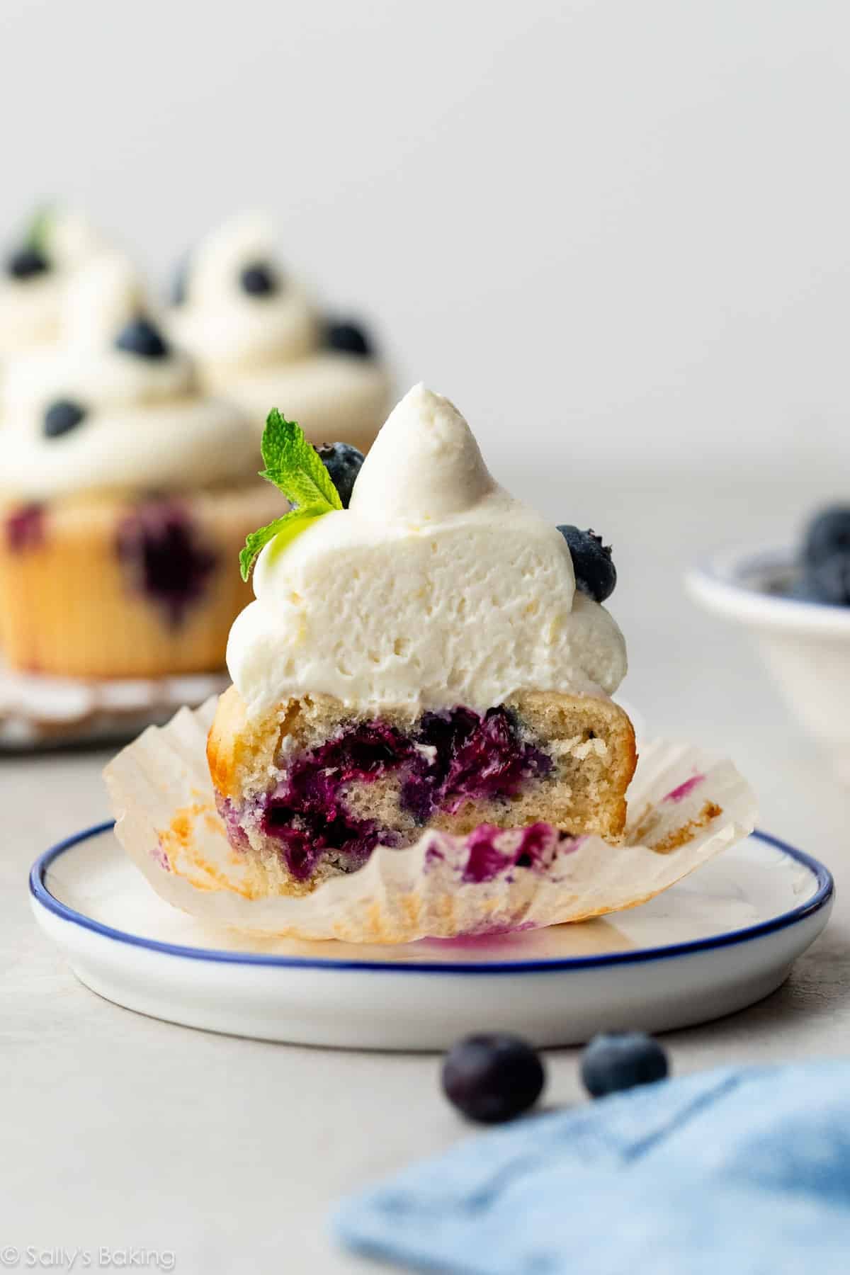 blueberry cupcakes cut in half with whipped cream cheese frosting on top.