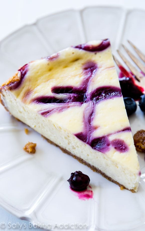 slice of blueberry swirl cheesecake on a white plate with a fork