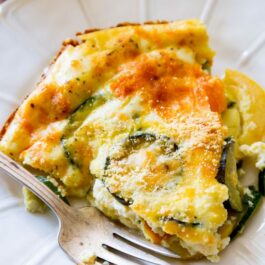 slice of crustless veggie quiche on a white plate with a fork