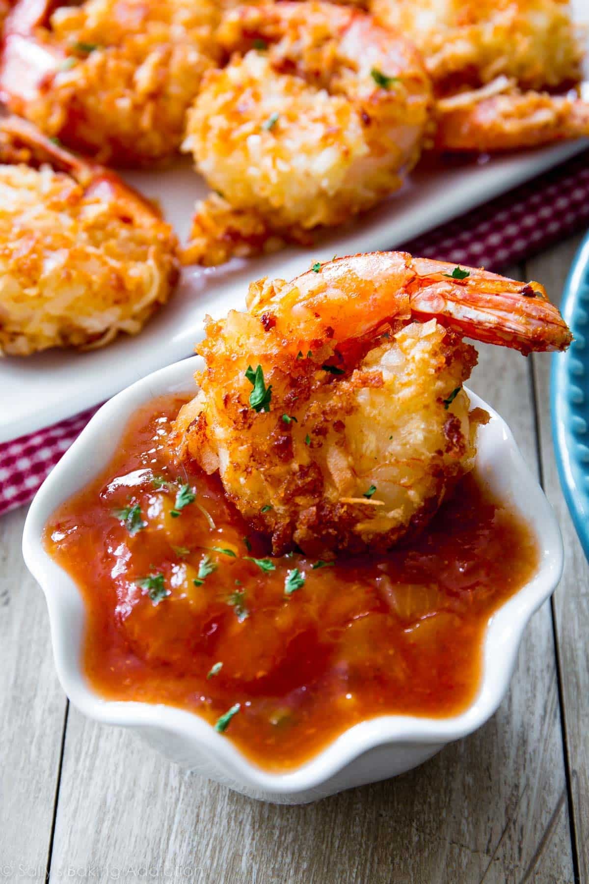 coconut shrimp dipped in ramekin of sweet orange chili sauce.