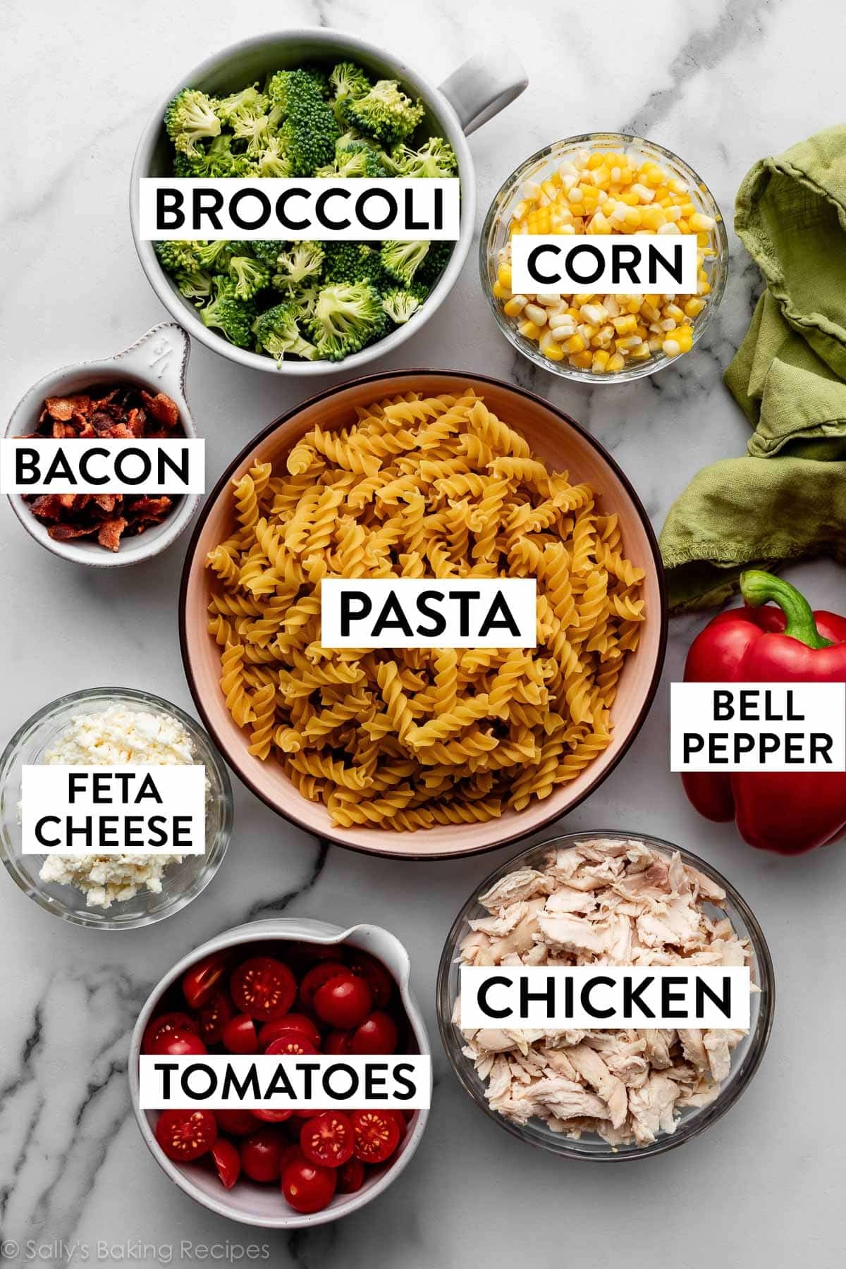 ingredients on counter including dry pasta, corn, broccoli, cooked chopped bacon, feta cheese, and bell pepper.