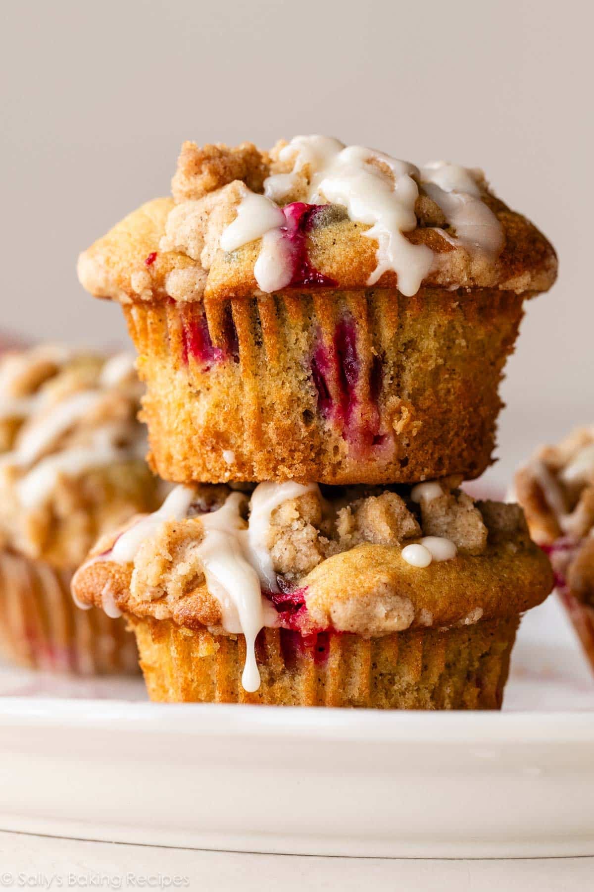 stack of 2 cranberry crumb orange muffins with icing on top.
