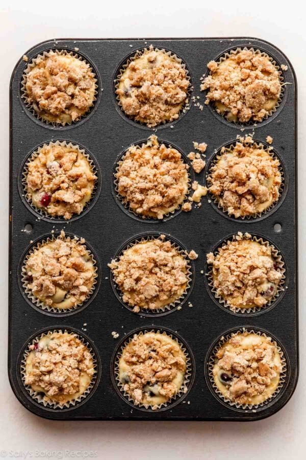 muffins with crumb topping pictured in muffin pan.