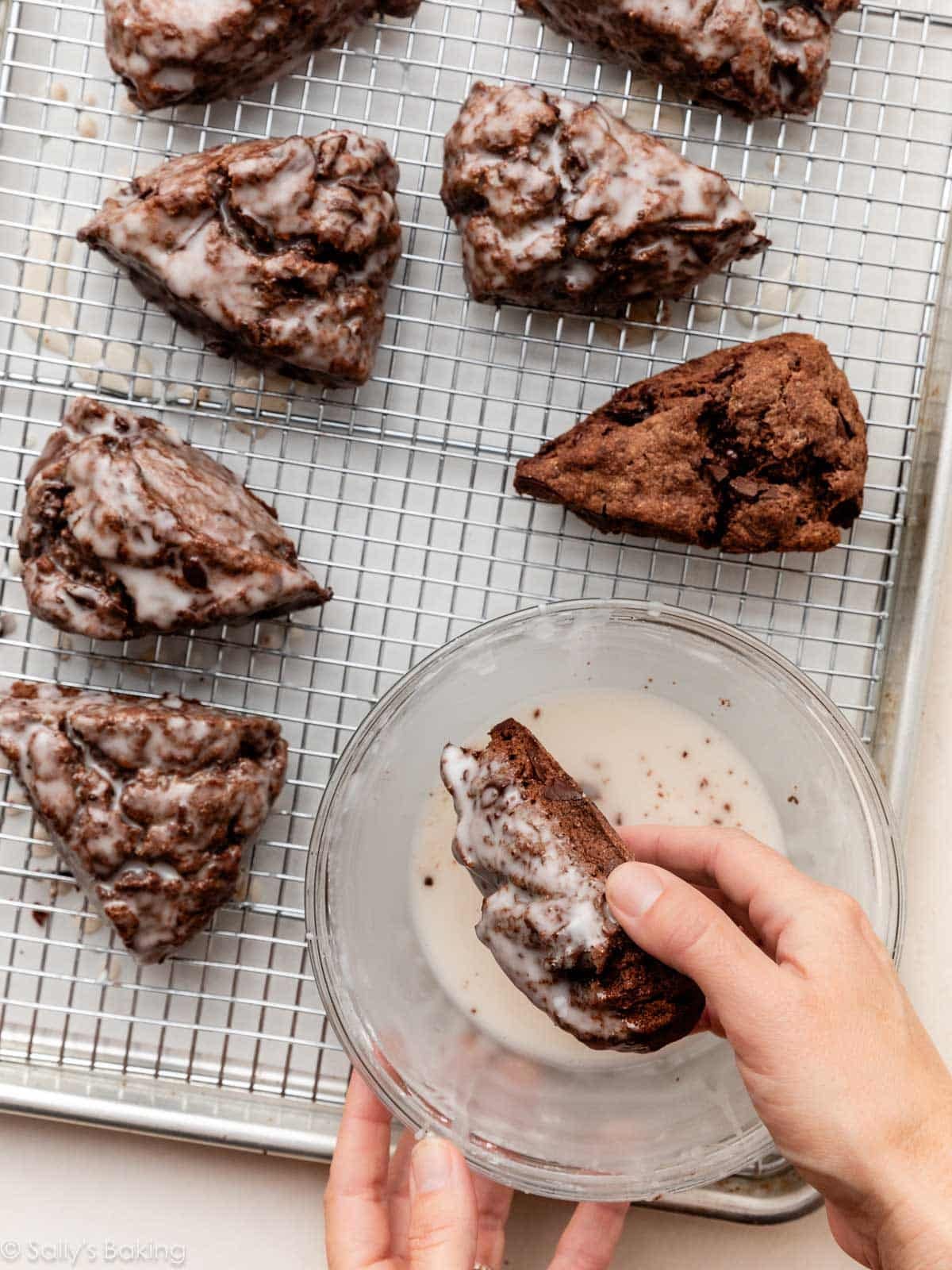 dipping chocolate scone into glaze.