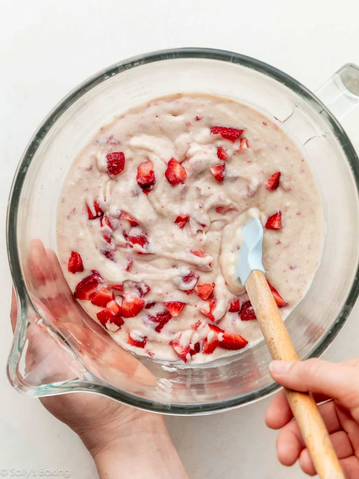 hands folding berries into batter.