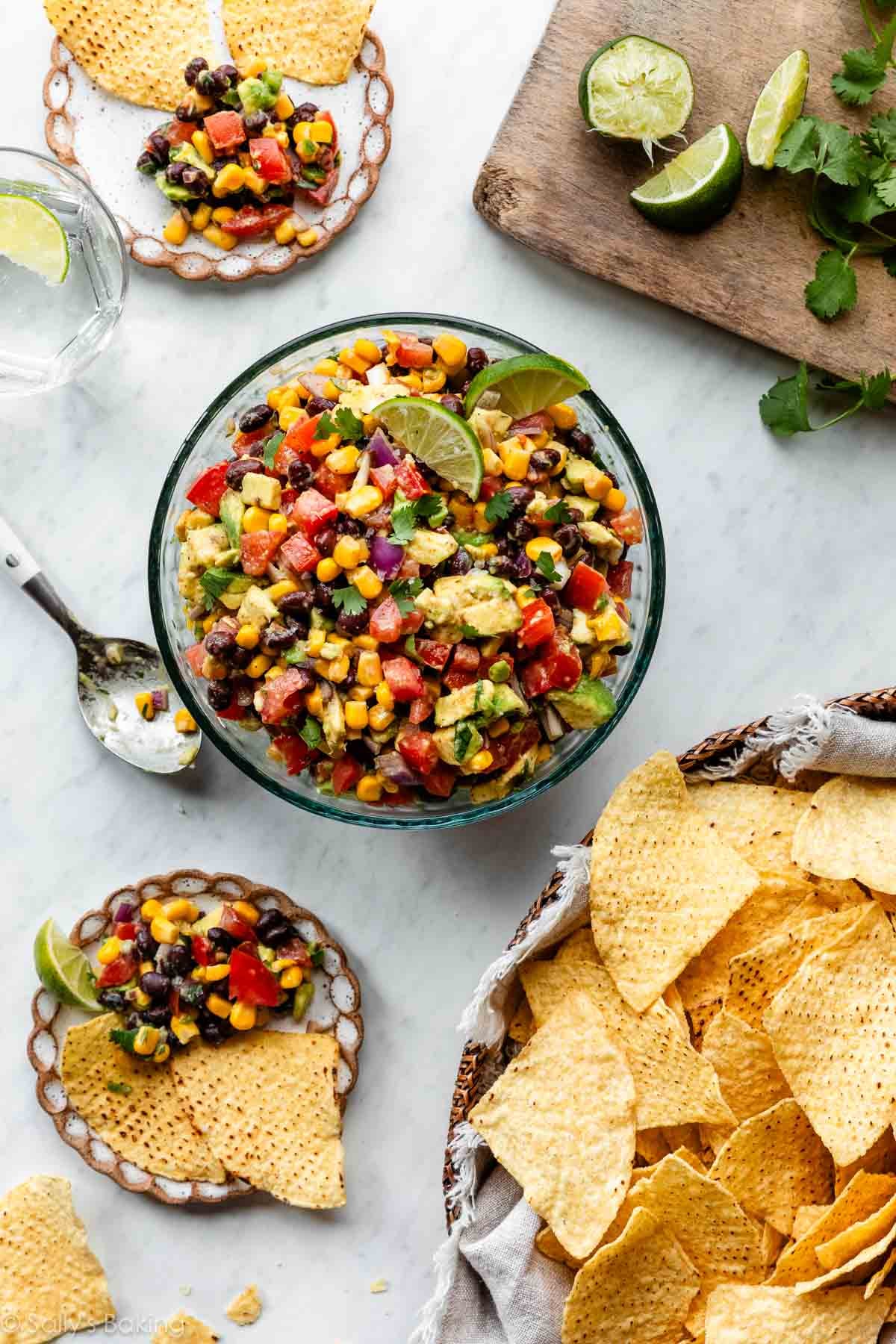 bowl of avocado black bean corn salsa with limes and tortilla chips.