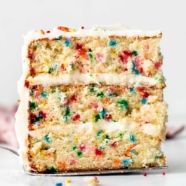slice of Funfetti confetti birthday cake with vanilla buttercream sitting on cake server.
