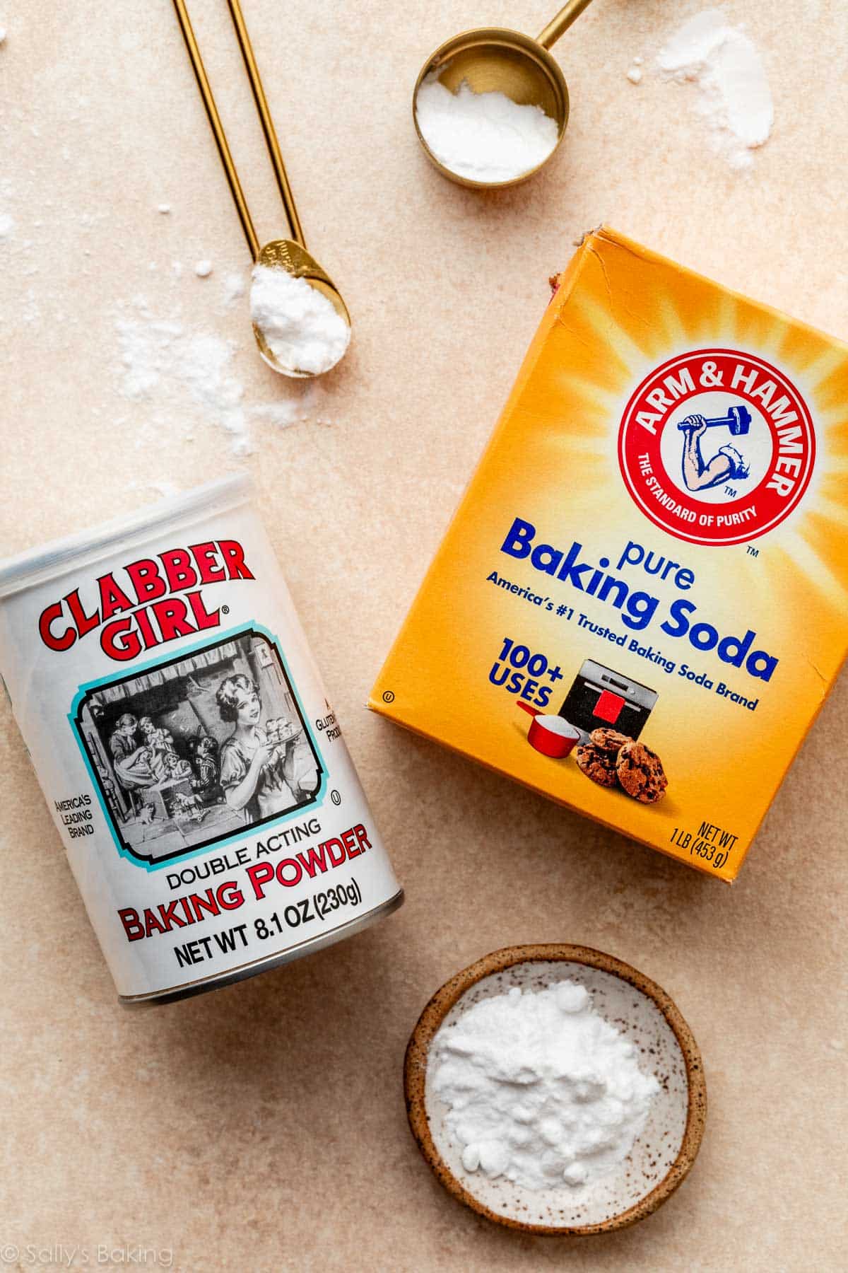 box of baking soda and container of baking powder on peach surface.