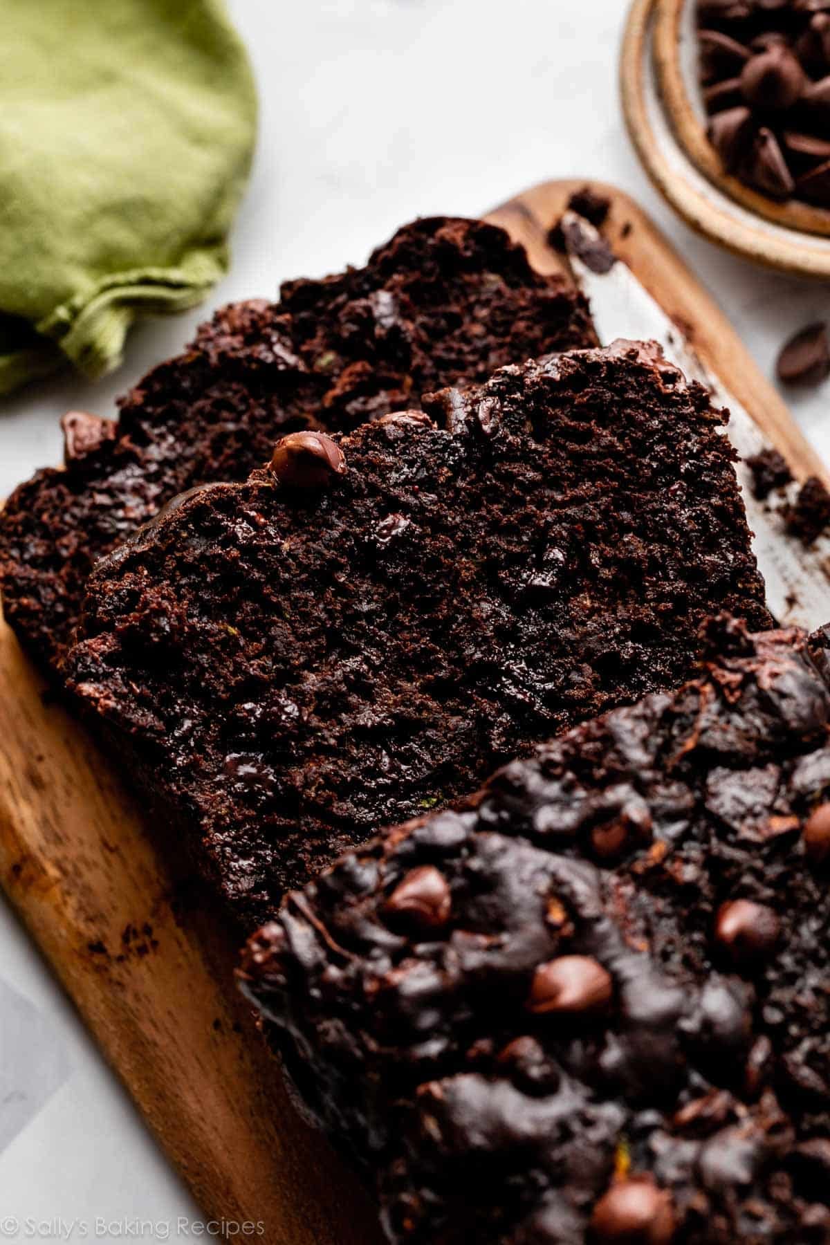 2 slices and the loaf of chocolate zucchini bread on wooden cutting board.