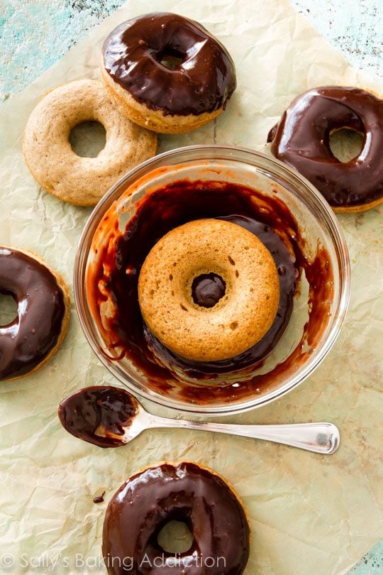 dunking a banana donut into a glass bowl of chocolate glaze