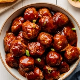 bbq meatballs in bowl with green onion garnish.
