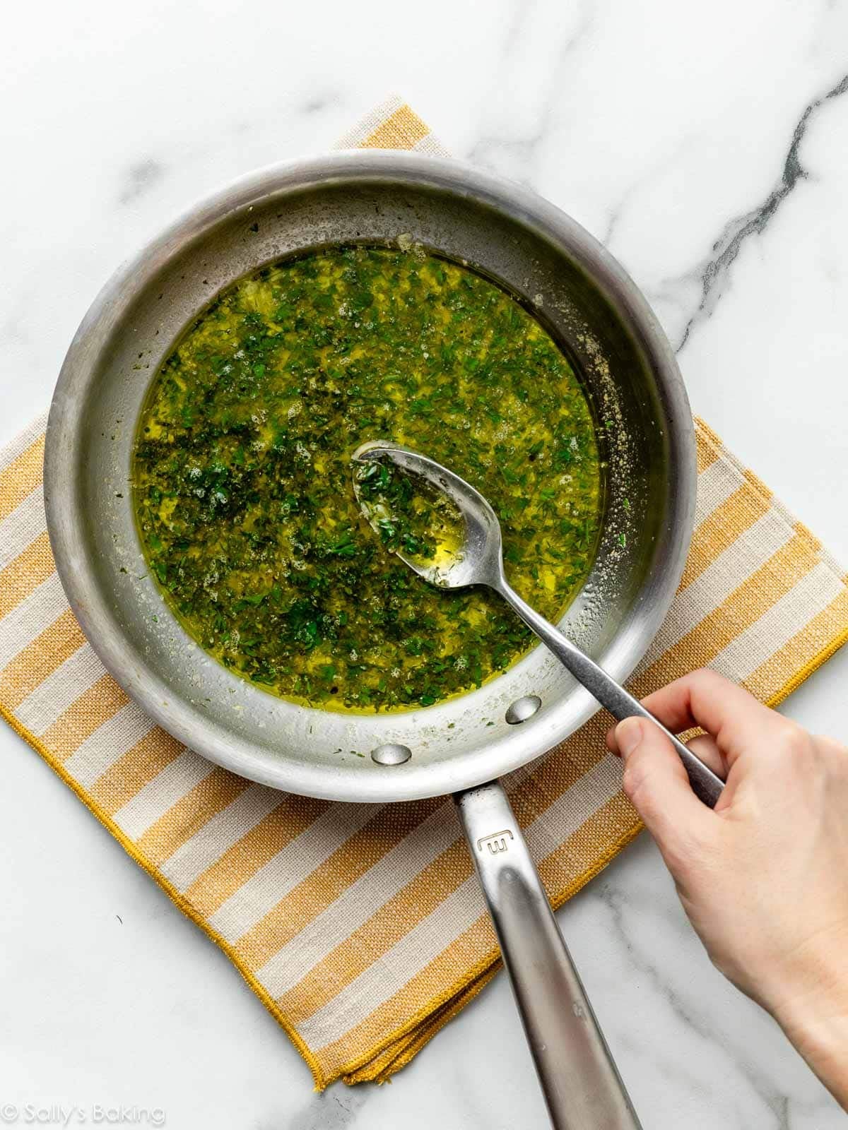 melted butter and herbs in small skillet placed on yellow striped linen.