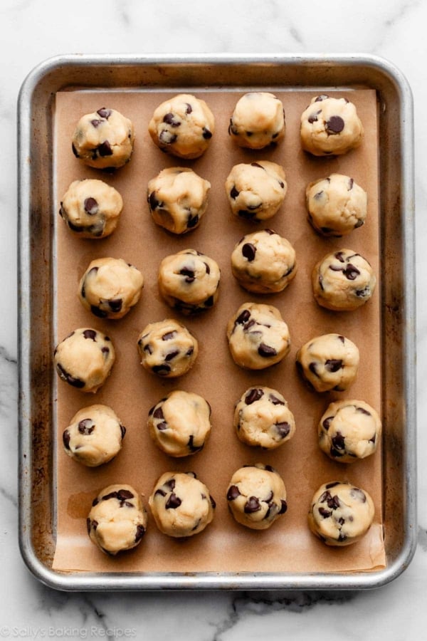 chocolate chip cookie dough balls on parchment paper-lined baking sheet.