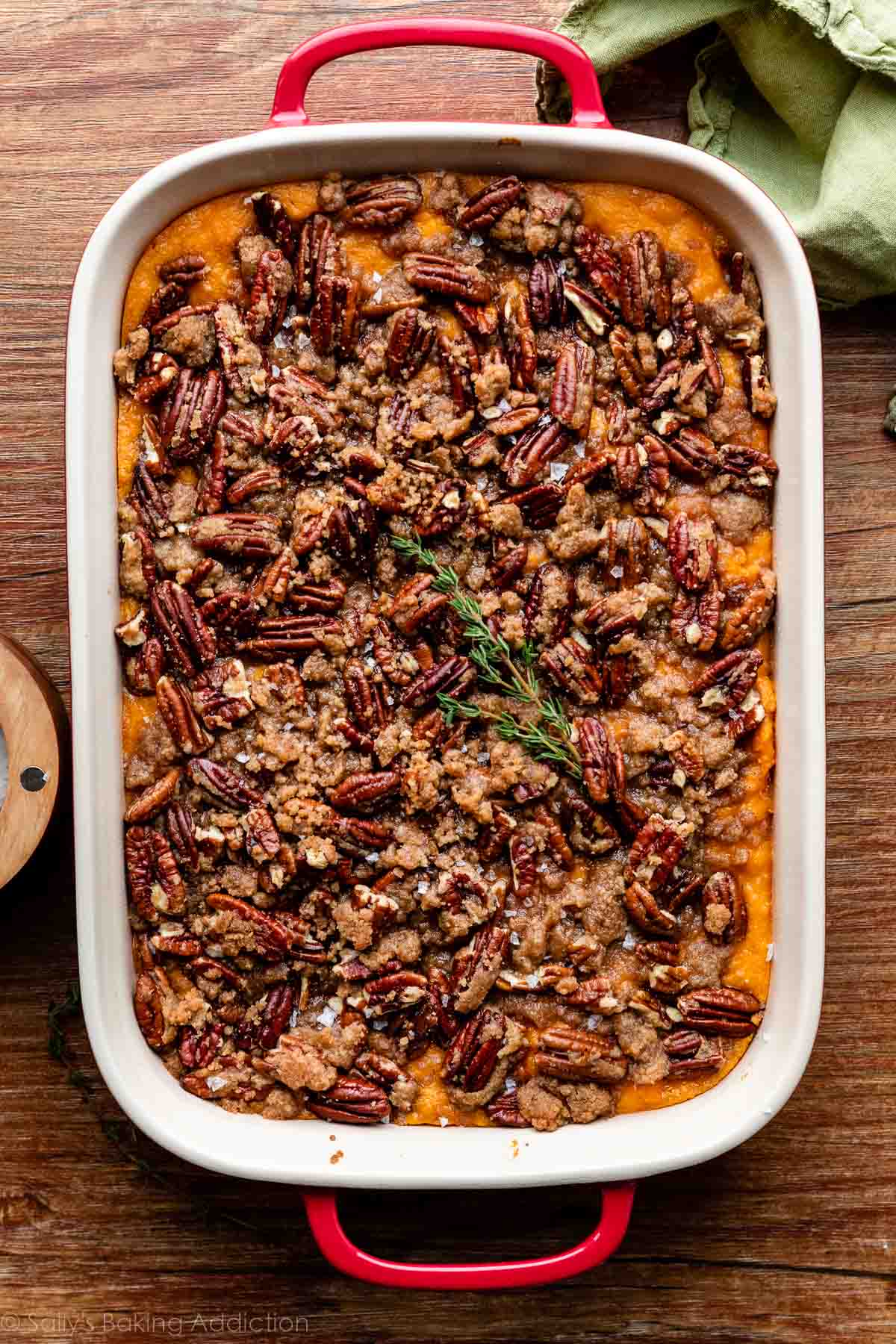 red and white casserole dish of sweet potato casserole topped with pecan crumble.