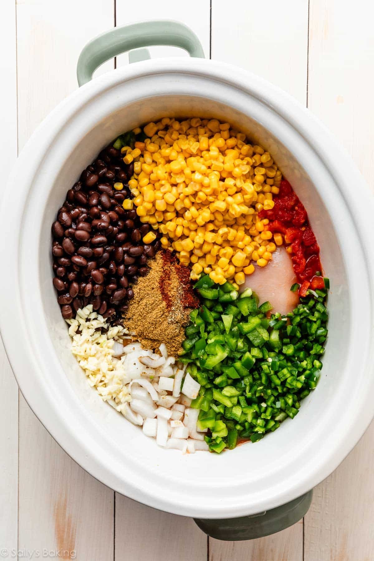 slow cooker with chopped onions and pepper, corn, black beans, spices, and tomato.