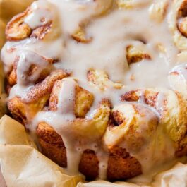 slow cooker cinnamon rolls with maple icing on parchment paper