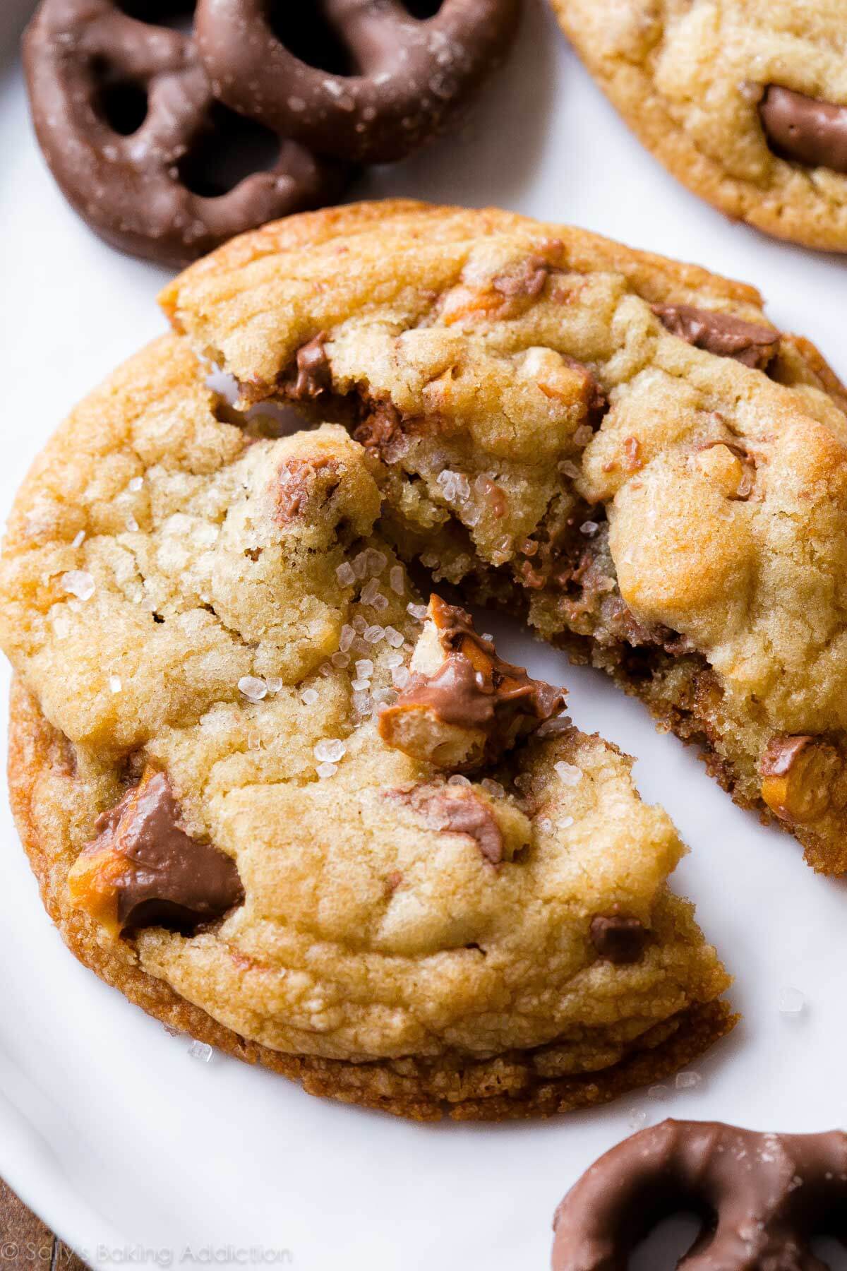 chocolate covered pretzel cookie broken in half on a white plate