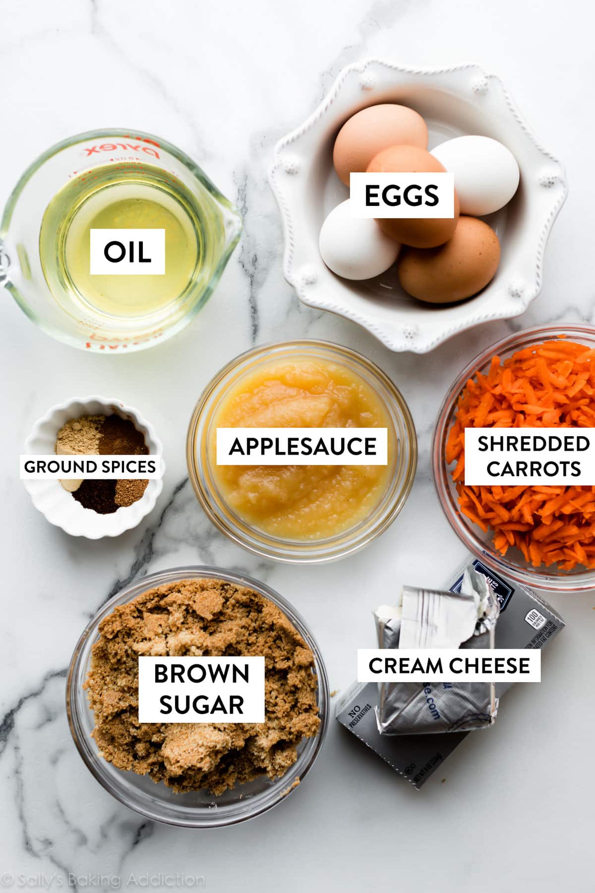 applesauce, shredded carrots, eggs, spices, and other ingredients pictured in bowls