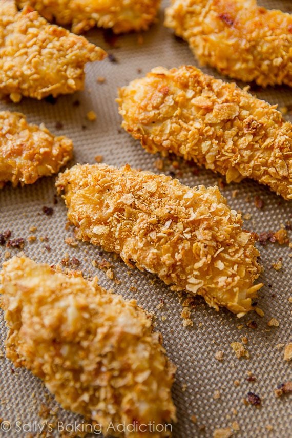 chicken fingers coated in cornflake mixture on a silpat baking mat