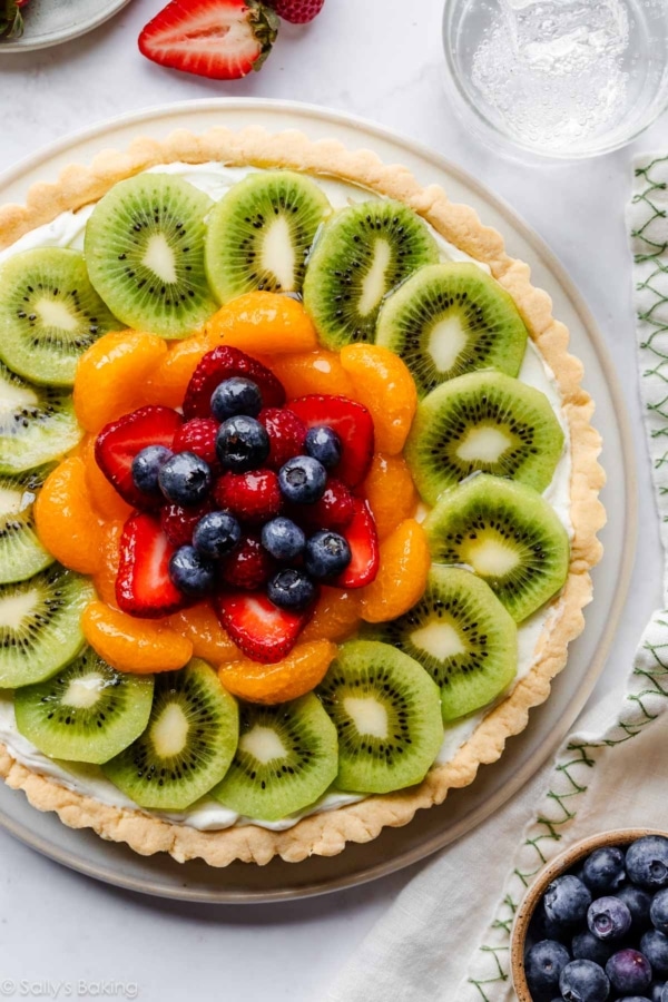 overhead image of fresh fruit tart with glass of sparkling water.