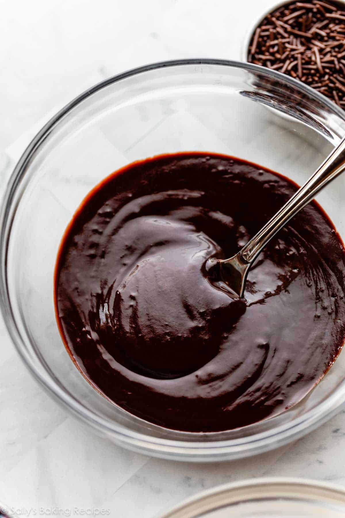chocolate frosting glaze in glass bowl with spoon in it.
