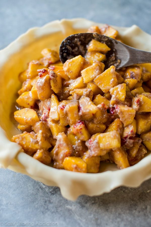 peach pie filling in pie dish with wood spoon