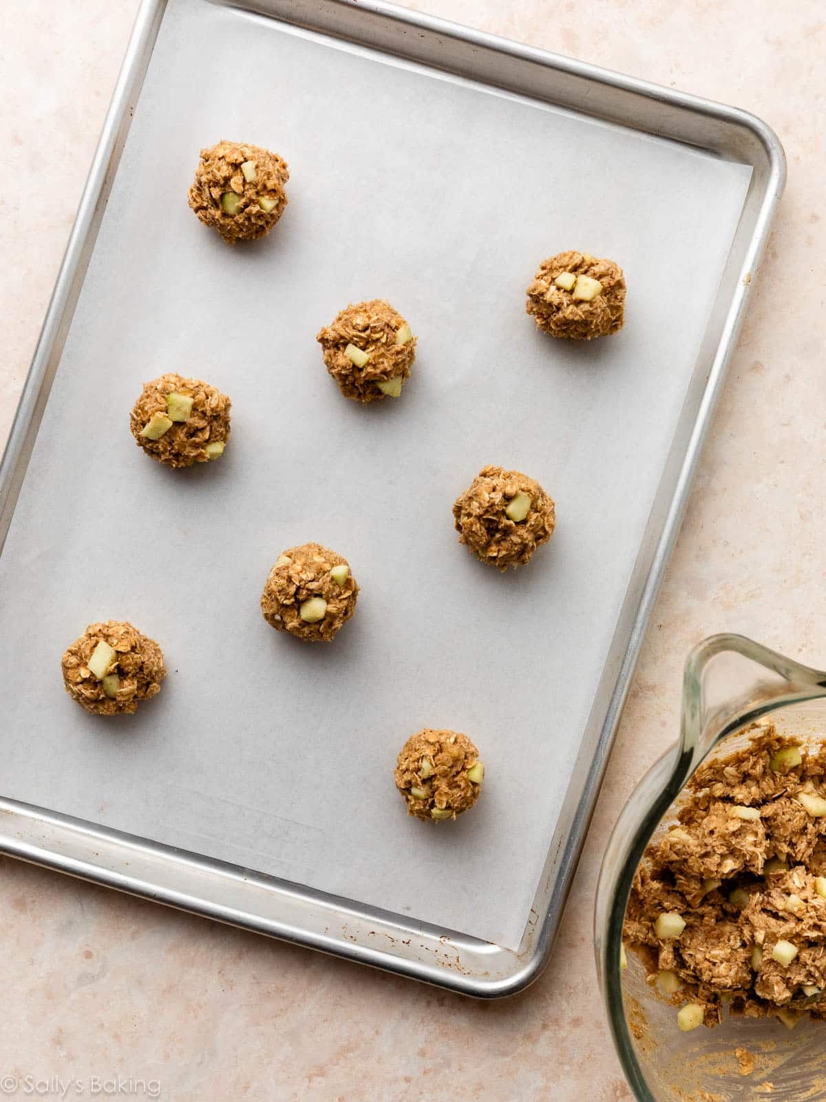 apple cookie dough balls on parchment paper-lined baking sheet.