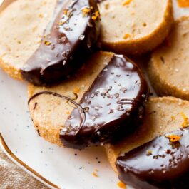 orange slice and bake cookies with half of each cookie dipped in dark chocolate on a white plate