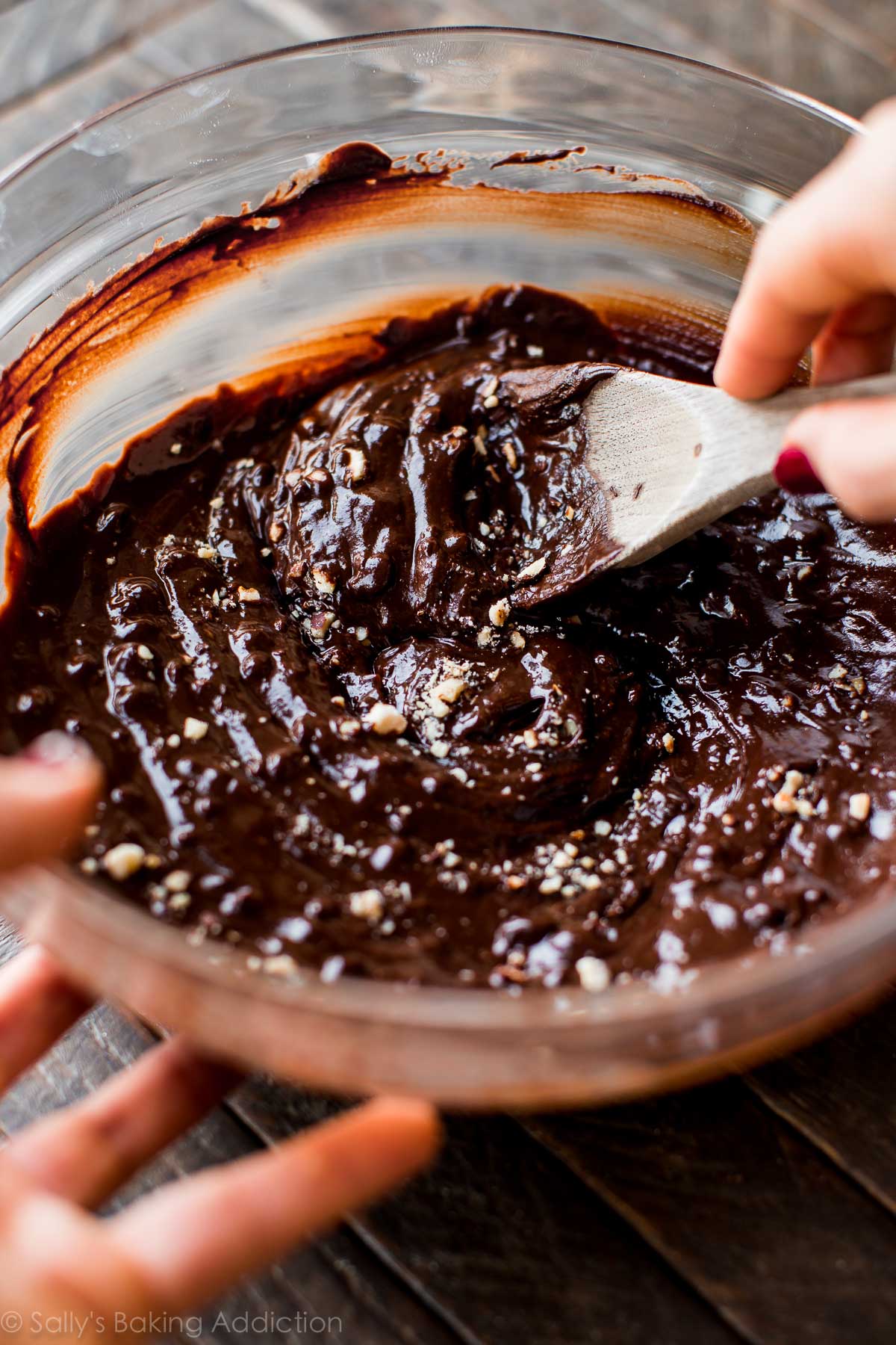 chocolate truffle filling with chopped hazelnuts in a glass bowl with a wood spoon