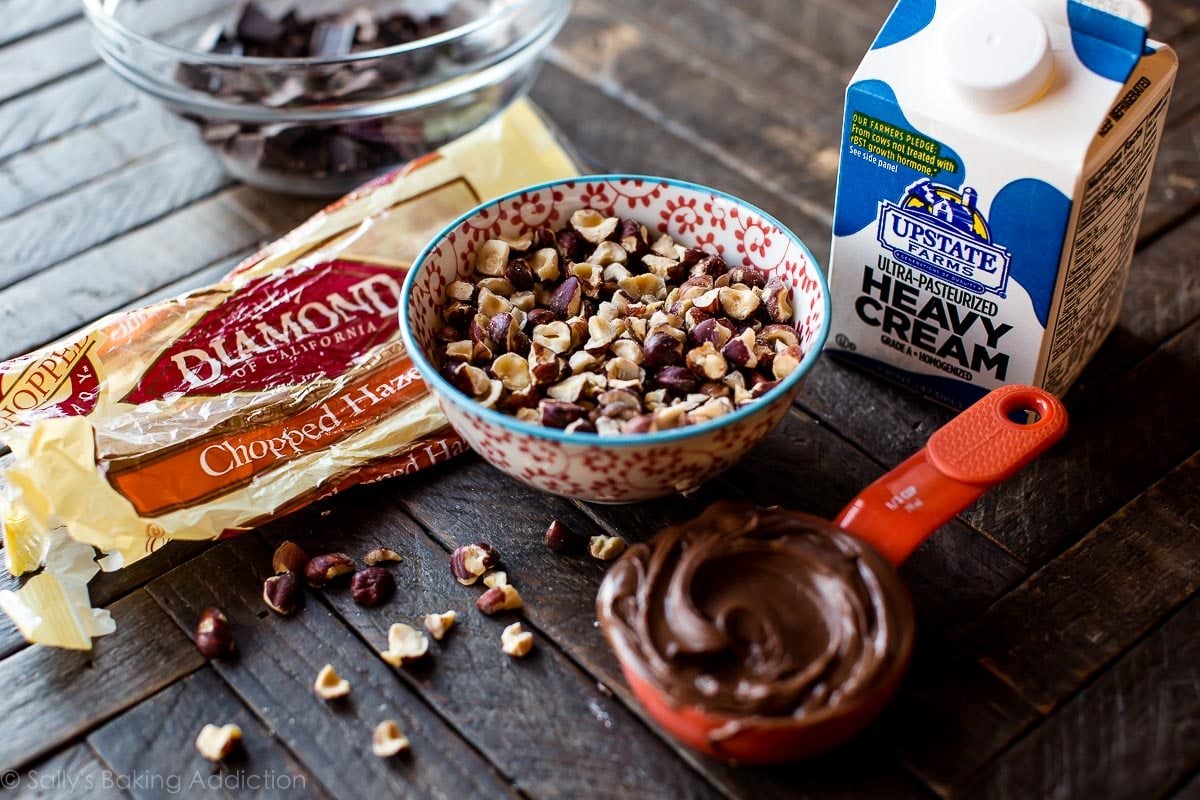 ingredients for chocolate hazelnut truffles including chopped hazelnuts in a bowl, Nutella in a measuring cup, and heavy cream