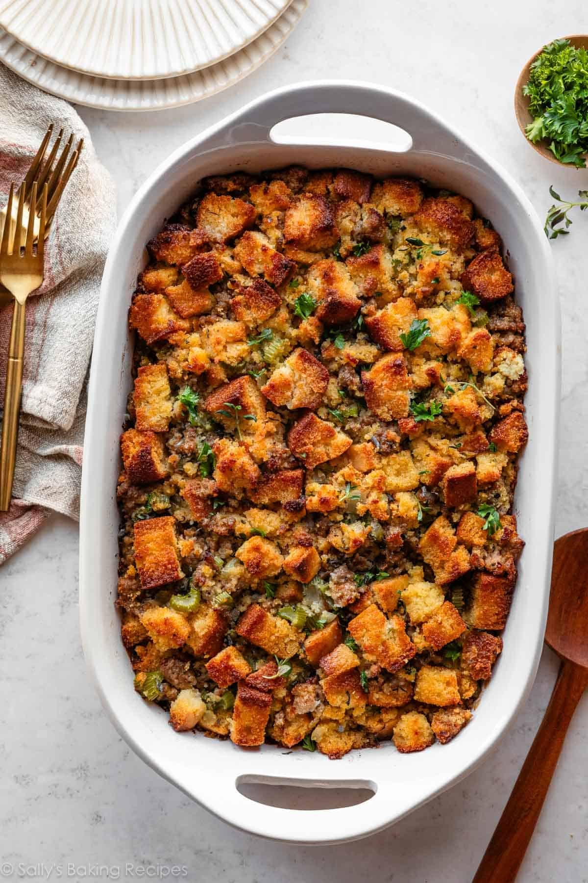 cornbread stuffing with sausage and herbs in white casserole dish.