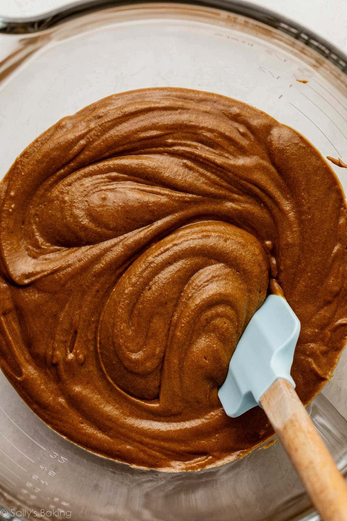 gingerbread batter in glass bowl with blue spatula.