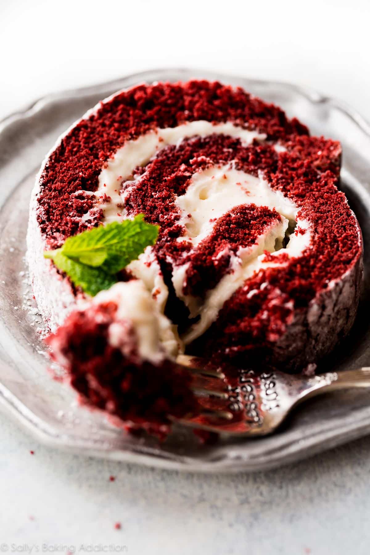 slice of red velvet cake roll on a silver plate with a fork