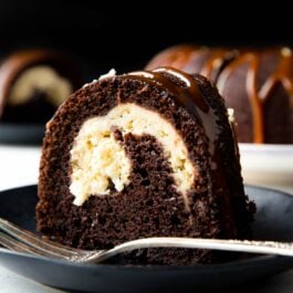 slice of chocolate cream cheese bundt cake on a black plate with a fork