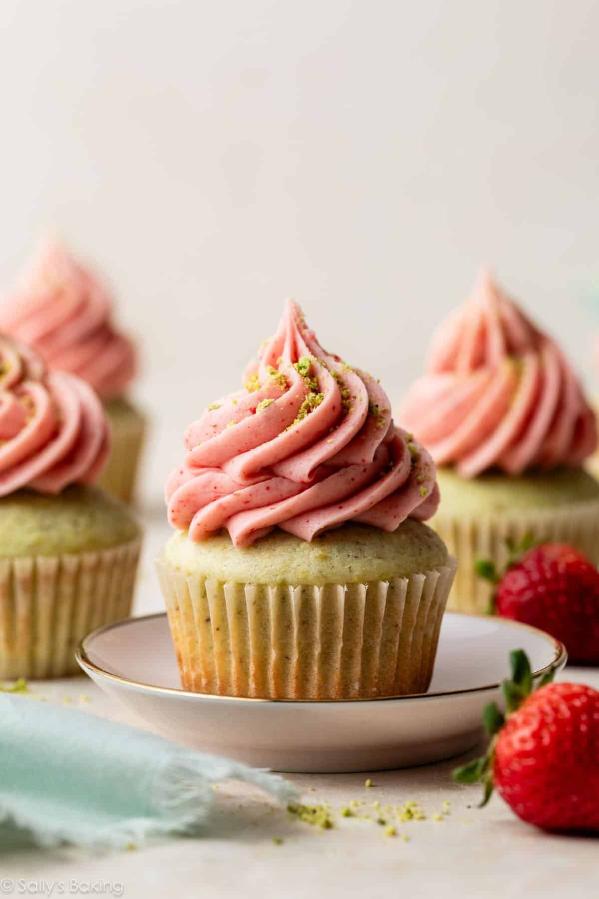 pistachio cupcake with strawberry buttercream piped on top.